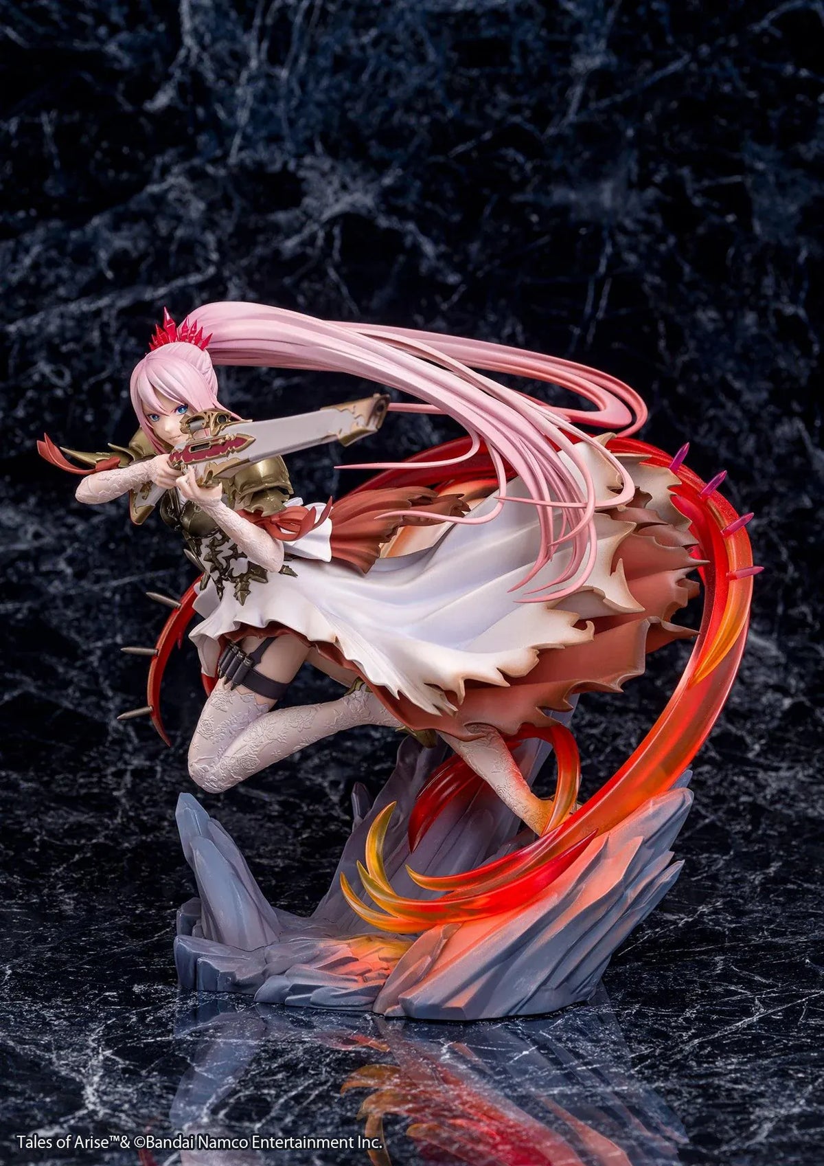 Tales of Arise Shionne 1/7 Scale Figure featuring a pink-haired anime character with blue eyes, an ornate white battle dress, gold armor, and lace stockings, aiming a detailed rifle while suspended in a dynamic pose surrounded by translucent red and orange effects on a rocky display base.