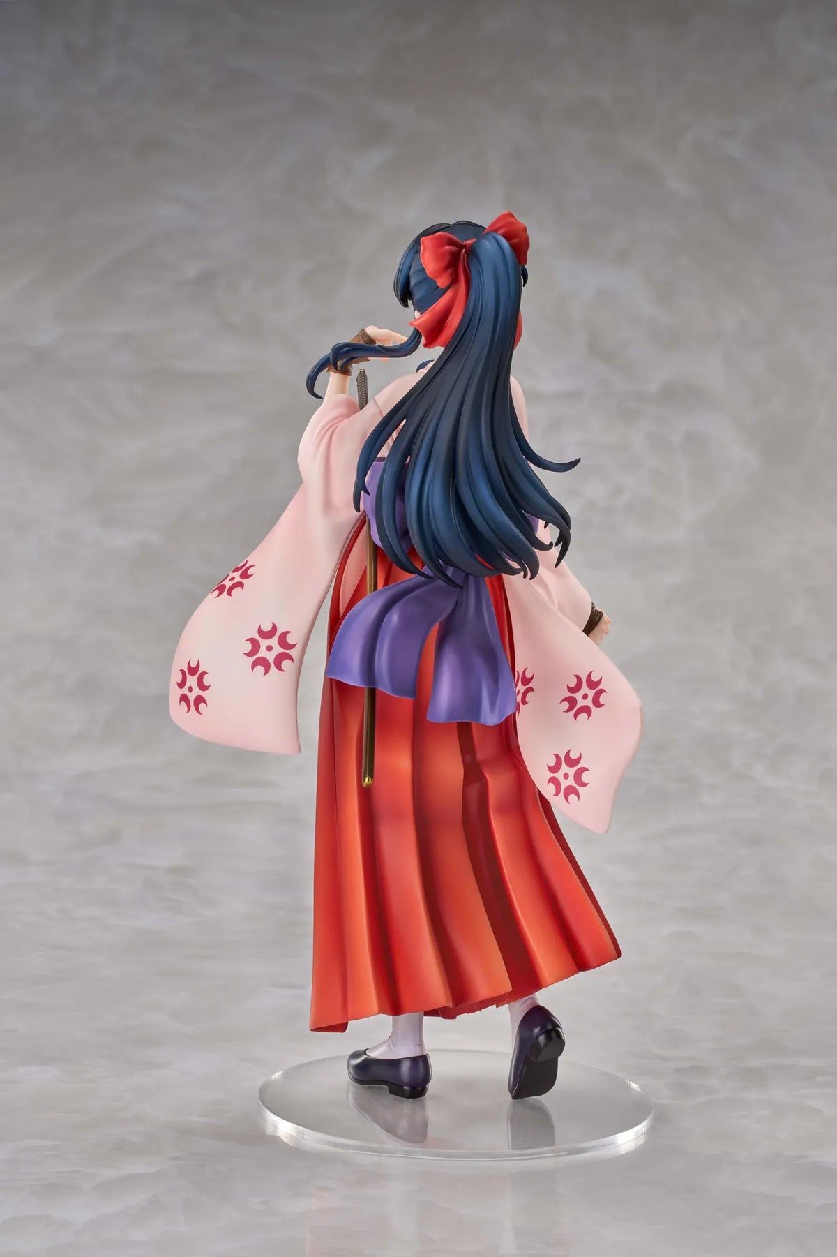 Sakura Wars Sakura Shinguji 1/7 Scale Figure featuring a dark blue-haired anime girl with brown eyes, a red hair ribbon, pink kimono-style top, purple obi, flowing red hakama skirt, sword accessory, and purple pouch on a transparent circular base.