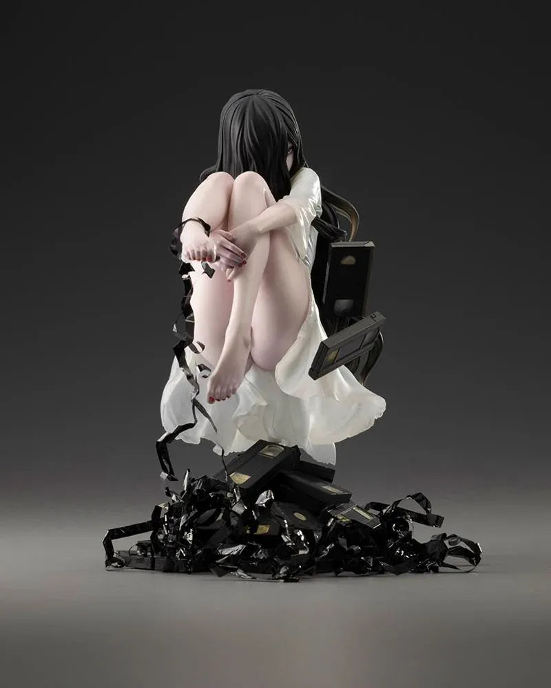 Sadako BISHOUJO Sadako 1/7 Scale Figure (Rerelease) featuring a long black-haired horror character wearing a flowing white dress, seated above a pile of VHS tapes with tangled black film ribbons.