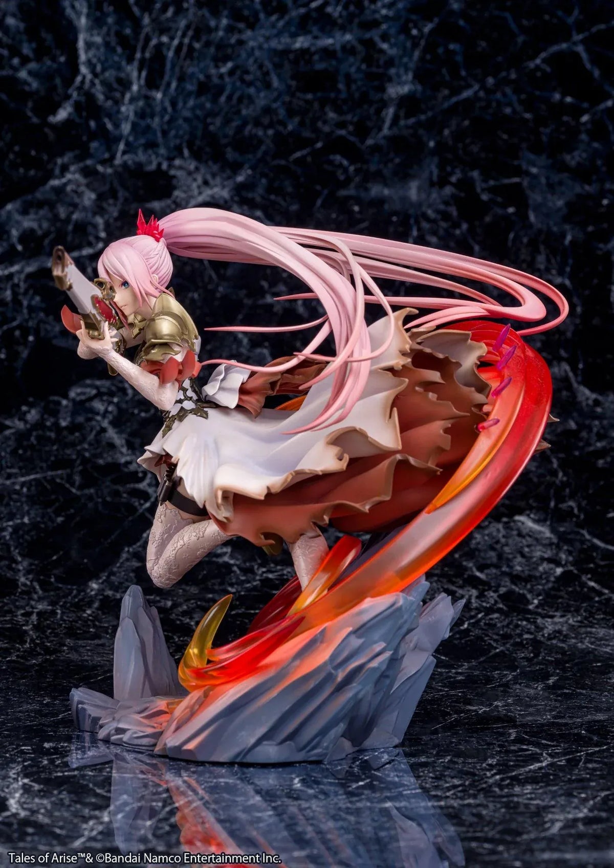 Tales of Arise Shionne 1/7 Scale Figure featuring a pink-haired anime character with blue eyes, an ornate white battle dress, gold armor, and lace stockings, aiming a detailed rifle while suspended in a dynamic pose surrounded by translucent red and orange effects on a rocky display base.