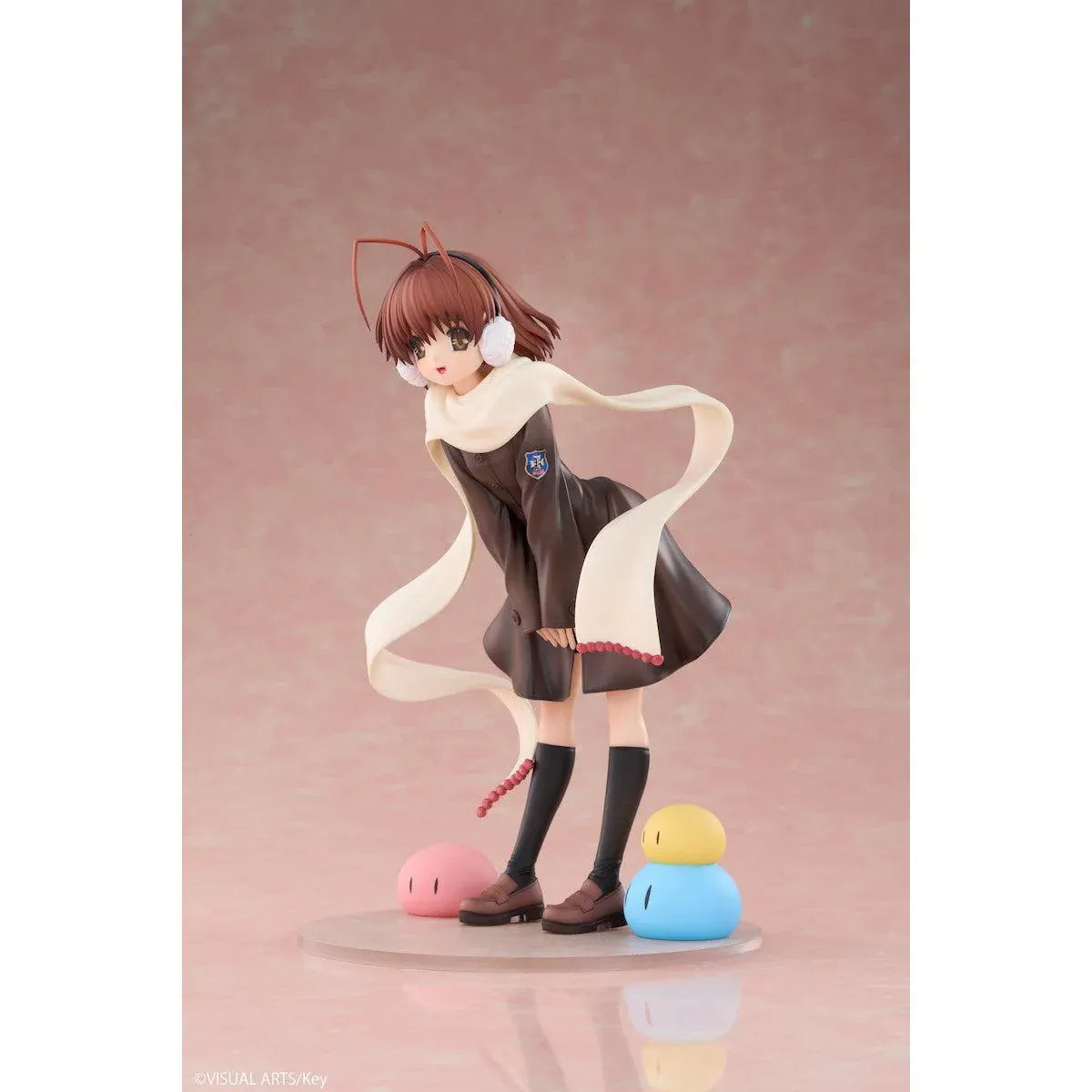CLANNAD Nagisa Furukawa 1/6 Scale Figure featuring a smiling brown-haired anime girl wearing a dark school uniform, cream-colored scarf, white earmuffs, and black knee-high socks, surrounded by colorful Dango Daikazoku characters.