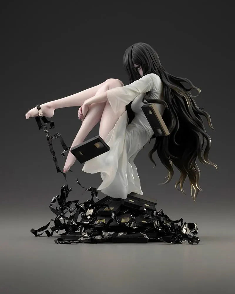 Sadako BISHOUJO Sadako 1/7 Scale Figure (Rerelease) featuring a long black-haired horror character wearing a flowing white dress, seated above a pile of VHS tapes with tangled black film ribbons.