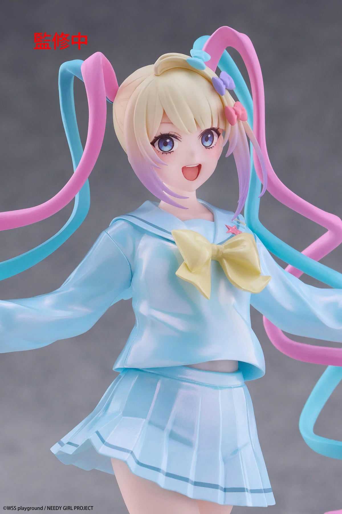 Needy Girl Overdose OMGKawaiiAngel Coreful Figure featuring a blonde-haired anime girl with blue eyes, long pink and blue twin-tails, a pastel-blue sailor-style outfit, yellow bow, and matching shoes posed on a pink heart-shaped base.