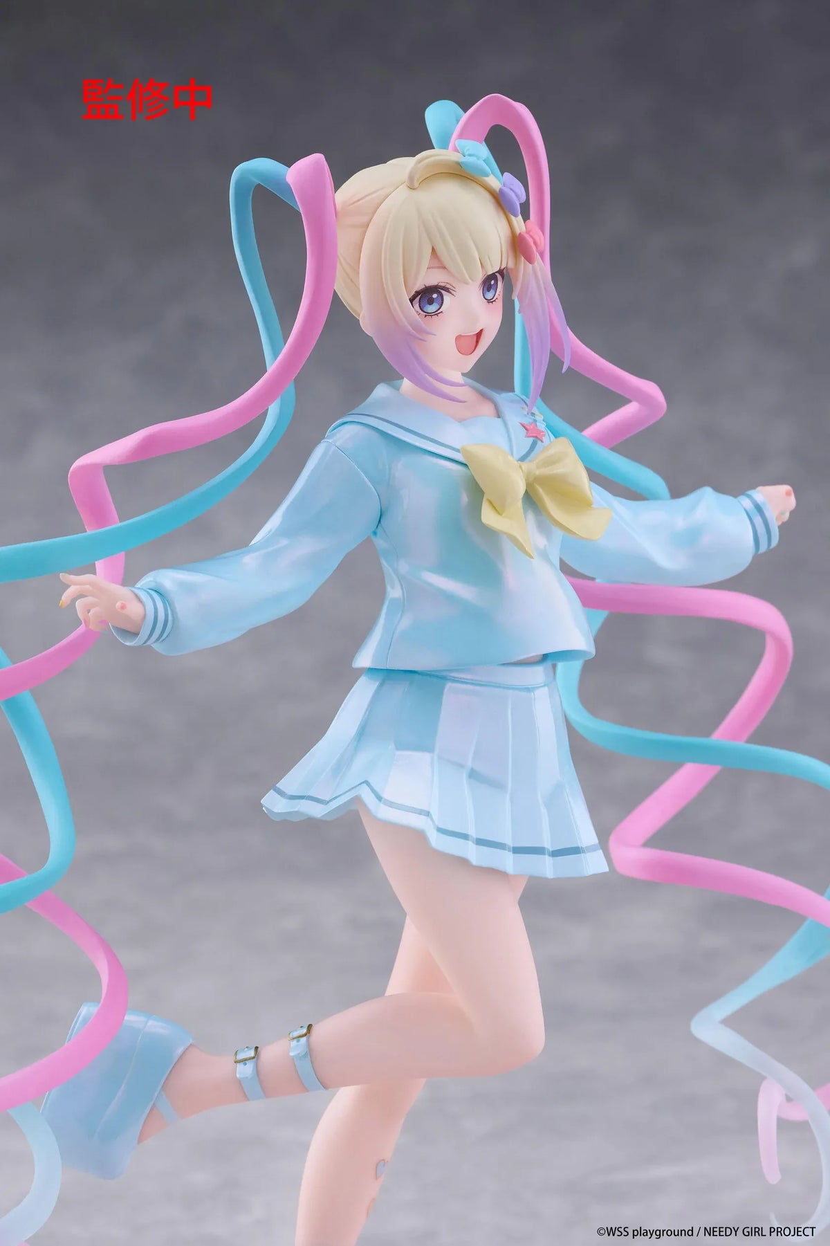 Needy Girl Overdose OMGKawaiiAngel Coreful Figure featuring a blonde-haired anime girl with blue eyes, long pink and blue twin-tails, a pastel-blue sailor-style outfit, yellow bow, and matching shoes posed on a pink heart-shaped base.