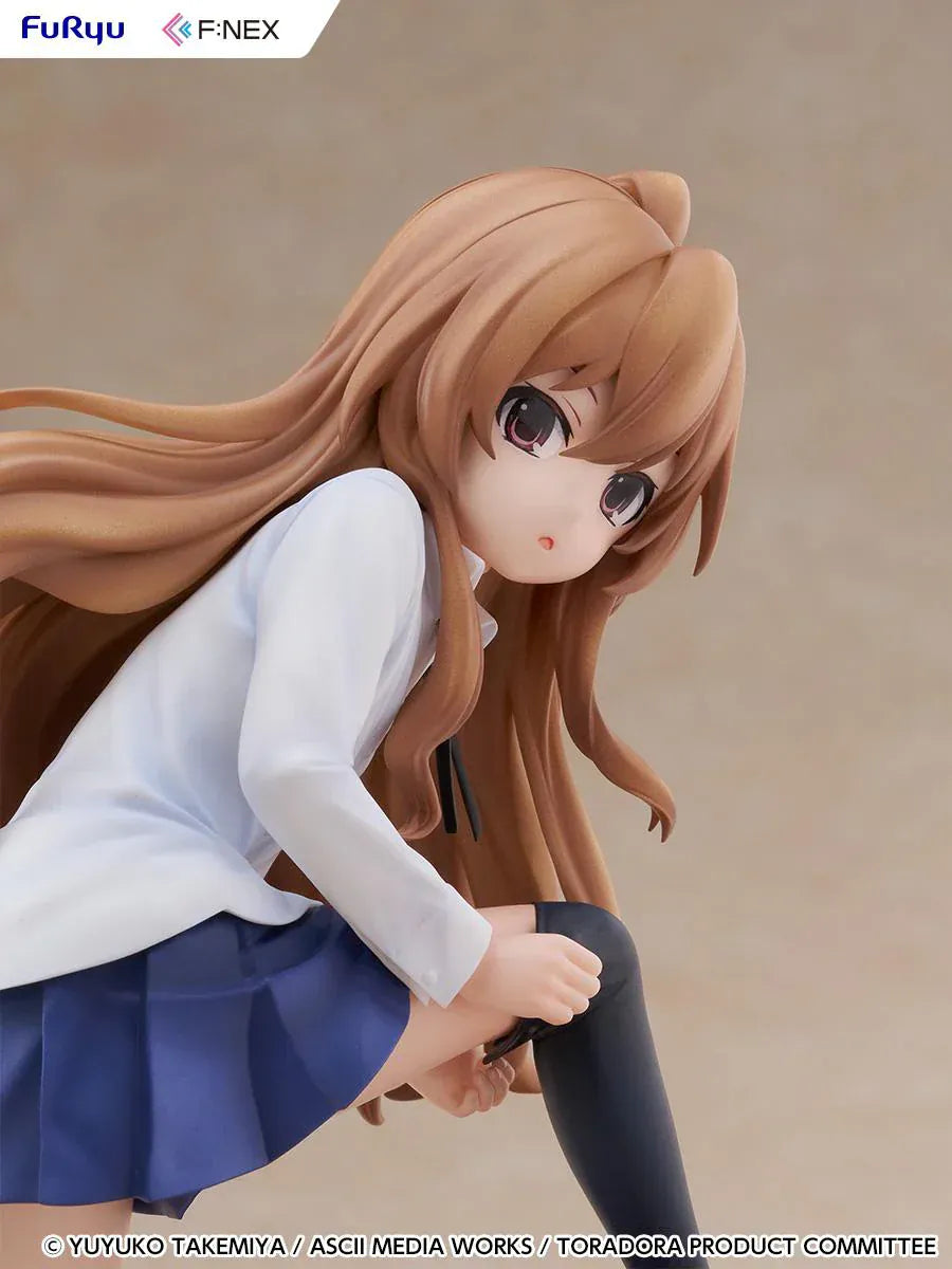 1/7 scale Toradora figure of Taiga Aisaka at home, barefoot and leaning on a leather armchair while pulling on a black thigh-high sock, wearing her school shirt and blue skirt.