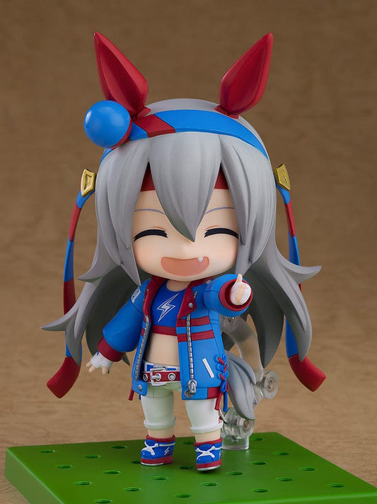 Uma Musume: Pretty Derby Nendoroid No.2703 Tamamo Cross, featuring Tamamo in a racing outfit, with expressive blue eyes and dynamic hair ribbons, posed energetically in her character's signature style.
