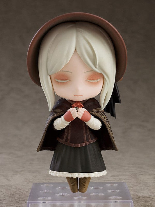 A Nendoroid of The Doll from Bloodborne, featuring a detailed brown Victorian dress, bonnet, cape with golden embroidery, and a small lantern accessory.