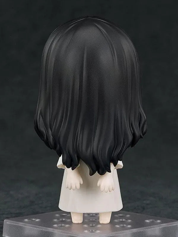 Nendoroid Sadako figure with long black hair covering her face, wearing a white dress and standing barefoot on a clear display base.