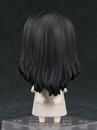 Nendoroid Sadako figure with long black hair covering her face, wearing a white dress and standing barefoot on a clear display base.