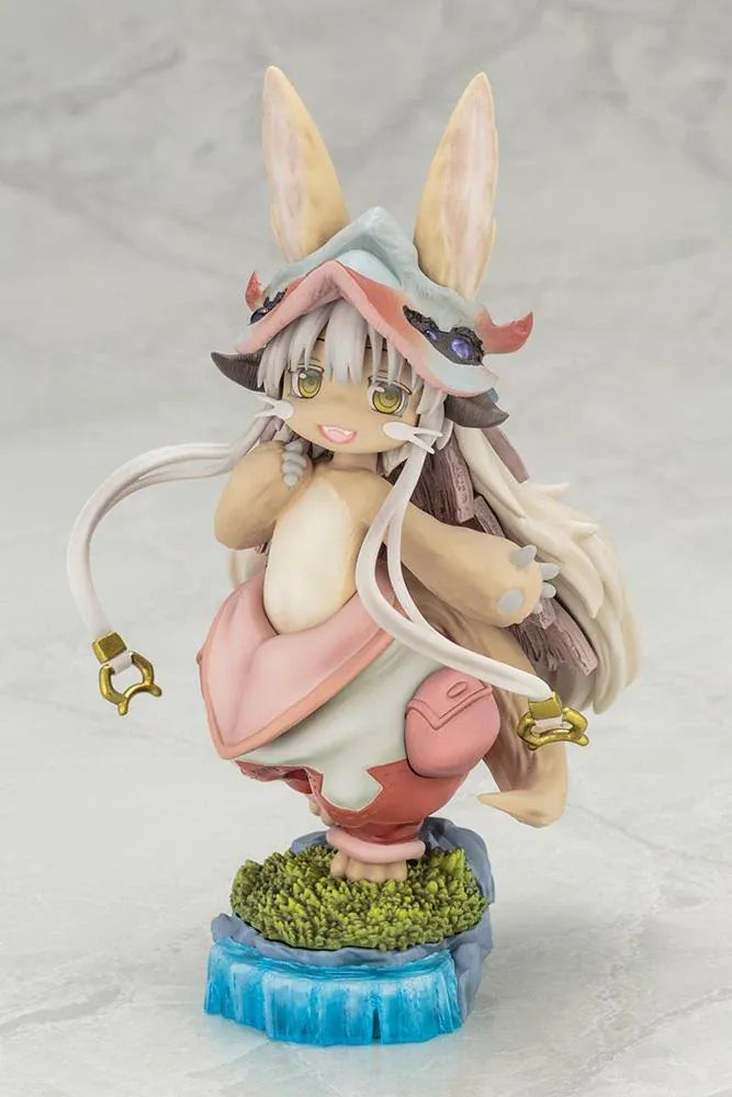 Made in Abyss The Awakening Mystery Nanachi Figure (Rerelease) featuring a fluffy rabbit-like character with long cream-colored ears, golden eyes, an oversized explorer hat, pink and beige clothing, and long flowing hair standing on a detailed scenic base with green moss, rocks, and blue water.