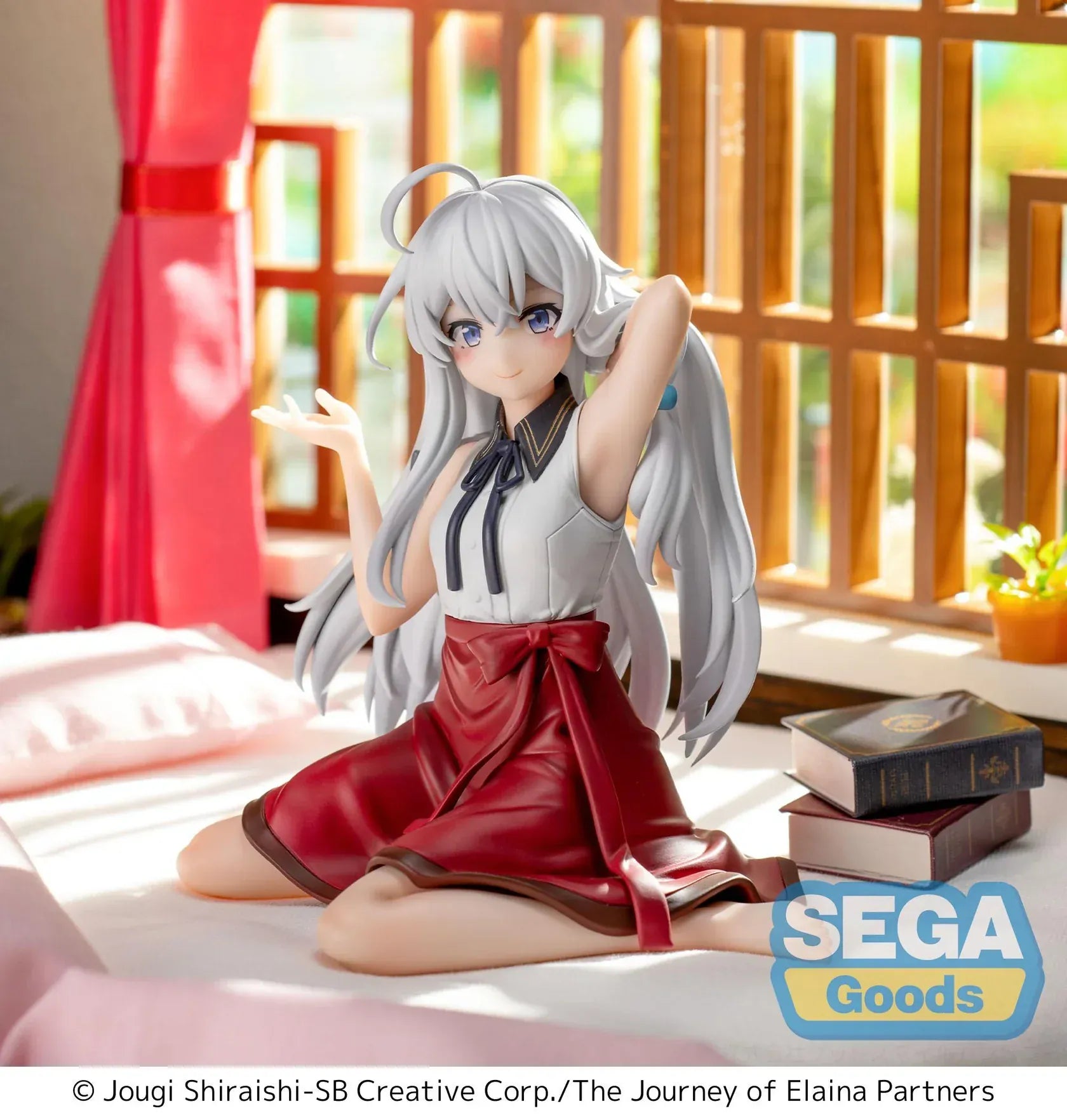 Figure of Elaina from Wandering Witch: The Journey of Elaina sitting on a bed in a white blouse and red skirt, with long silver hair and books beside her, in a sunlit room.