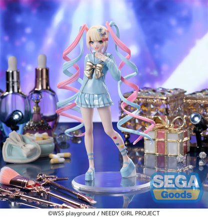Luminasta OMGKawaiiAngel figure from Needy Streamer Overload standing on a clear base, wearing a pastel blue school outfit with gold bow and long pink-and-blue spiral twin tails, surrounded by makeup and accessories.