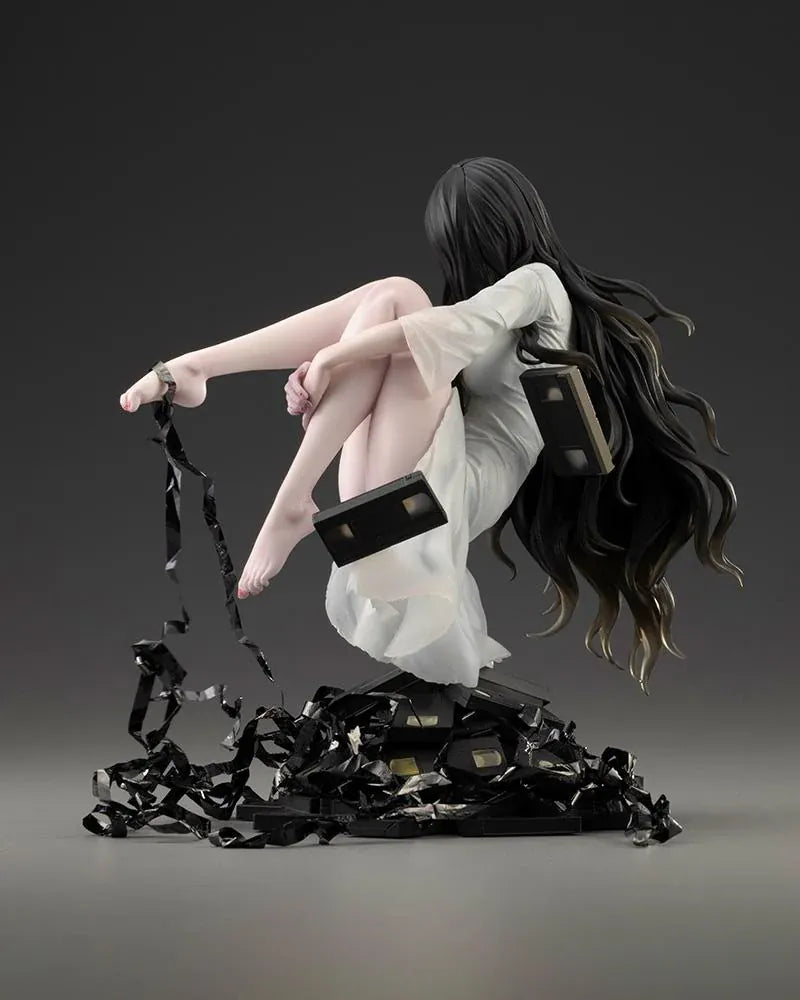 Sadako BISHOUJO Sadako 1/7 Scale Figure (Rerelease) featuring a long black-haired horror character wearing a flowing white dress, seated above a pile of VHS tapes with tangled black film ribbons.