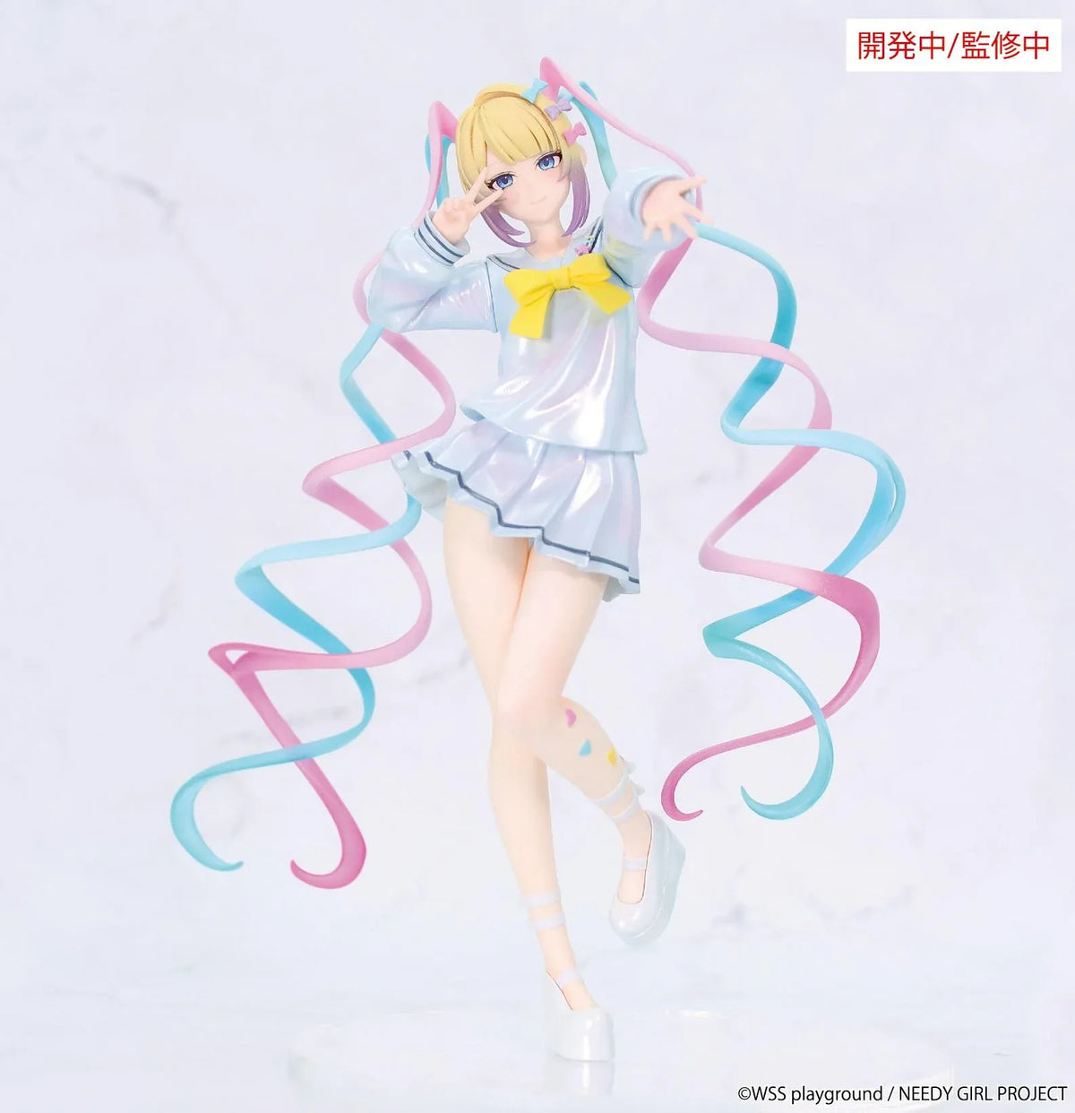 Prototype NEEDY GIRL OVERDOSE Vivit INTERNET ANGEL figure in a pale blue outfit with a yellow bow, spiraling pink-and-turquoise hair, and a peace-sign pose.