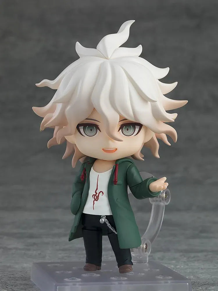 Nendoroid Nagito Komaeda with tousled white hair, pale green eyes, a green coat, white printed shirt, and black trousers, extending one hand.