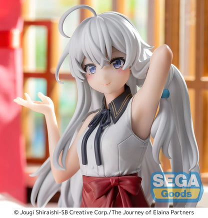 Figure of Elaina from Wandering Witch: The Journey of Elaina sitting on a bed in a white blouse and red skirt, with long silver hair and books beside her, in a sunlit room.