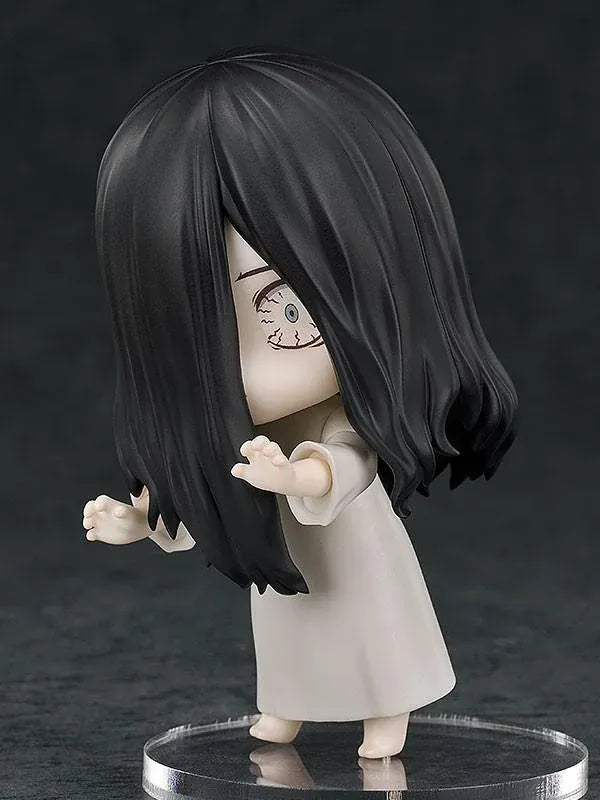 Nendoroid Sadako figure with long black hair covering her face, wearing a white dress and standing barefoot on a clear display base.