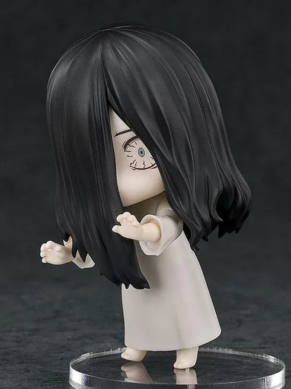 Nendoroid Sadako figure with long black hair covering her face, wearing a white dress and standing barefoot on a clear display base.