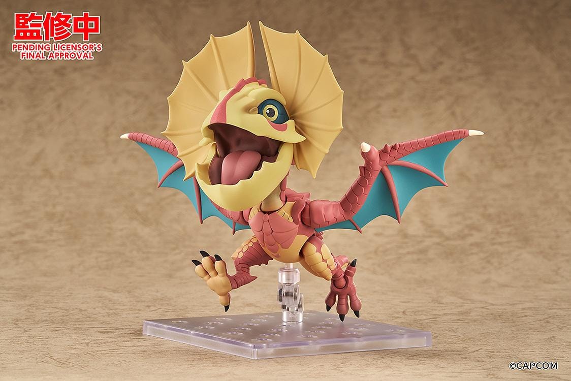 Monster Hunter Nendoroid Yian Kut-Ku with yellow ear fans, an open beak, pink-red scales, and spread wings with turquoise membranes.