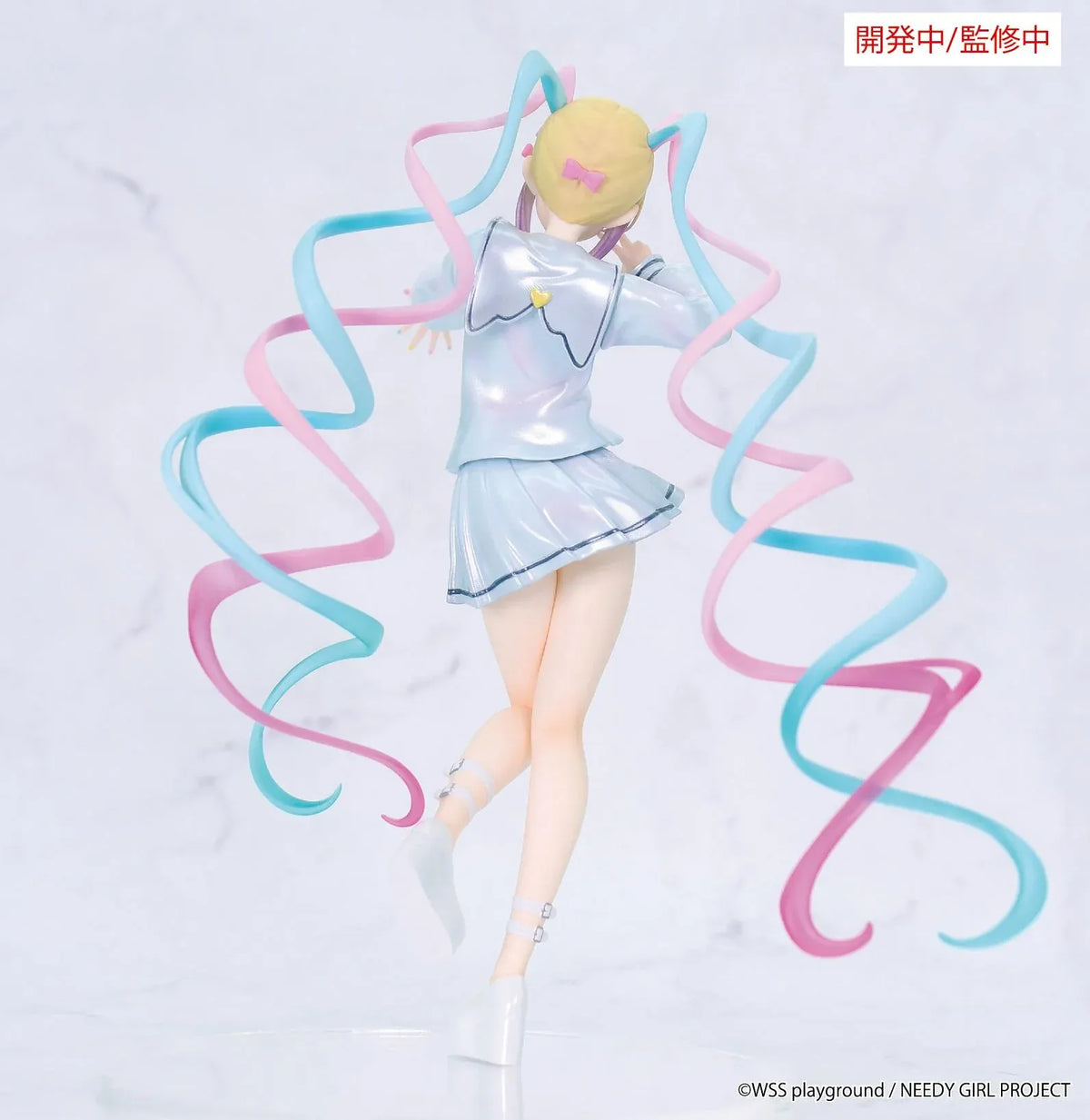 Prototype NEEDY GIRL OVERDOSE Vivit INTERNET ANGEL figure in a pale blue outfit with a yellow bow, spiraling pink-and-turquoise hair, and a peace-sign pose.