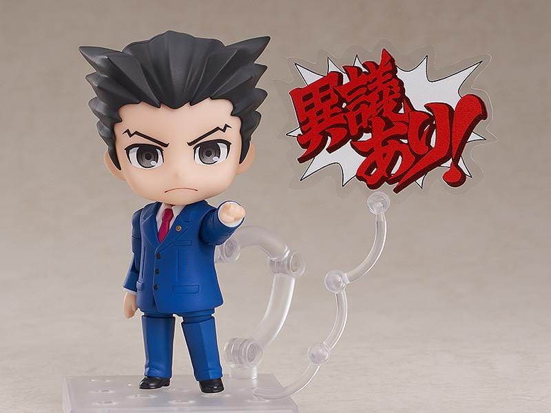 Ace Attorney Phoenix Wright Nendoroid rerelease figure wearing a blue suit and pointing beside a Japanese Objection effect part.