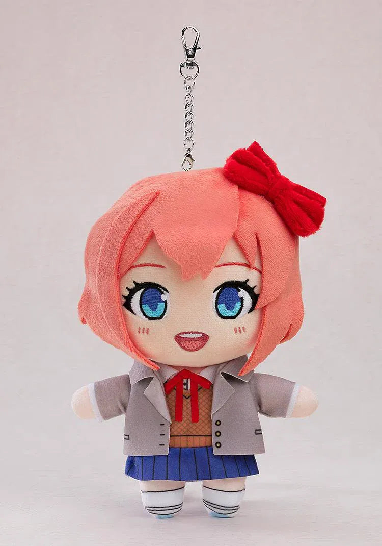 Doki Doki Literature Club! Sayori plushie keychain with coral-pink hair, a red bow, embroidered blue eyes, a school uniform, and a metal clasp.

