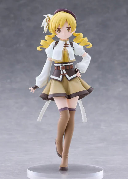 Mami Tomoe figure with blonde spiral curls, a brown hat, white and gold outfit, and tall brown boots, posing with one hand on her hip.