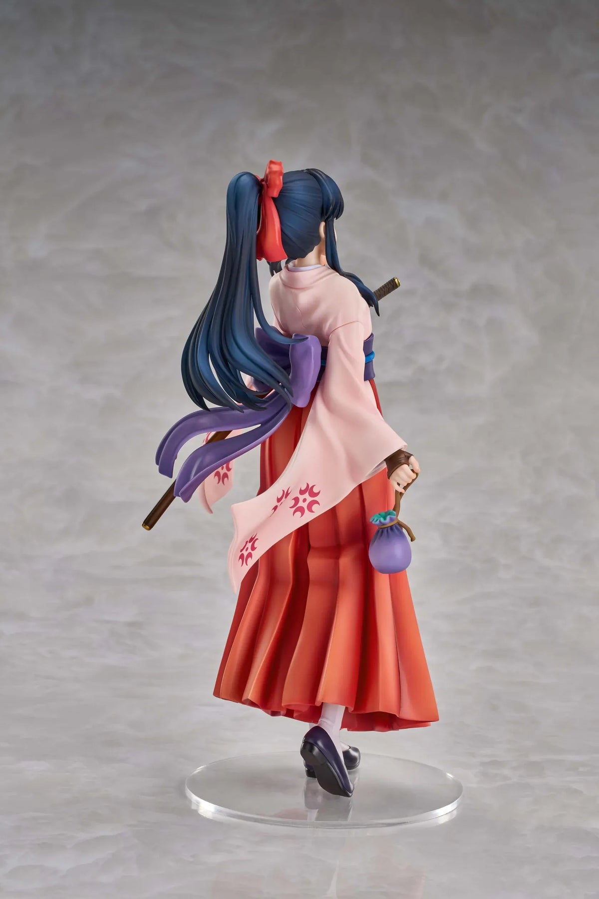 Sakura Wars Sakura Shinguji 1/7 Scale Figure featuring a dark blue-haired anime girl with brown eyes, a red hair ribbon, pink kimono-style top, purple obi, flowing red hakama skirt, sword accessory, and purple pouch on a transparent circular base.
