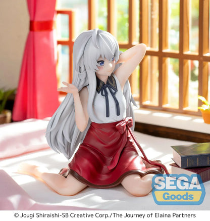 Figure of Elaina from Wandering Witch: The Journey of Elaina sitting on a bed in a white blouse and red skirt, with long silver hair and books beside her, in a sunlit room.