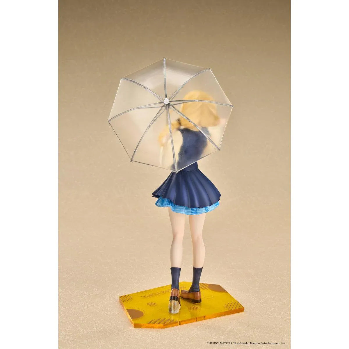 Gakuen iDOLM@STER Kotone Fujita Ameagari no Iris Before Special Training Ver. 1/7 Scale Figure featuring a blonde-haired anime girl with twin braids wearing a navy-blue school uniform and holding a transparent umbrella on a yellow display base.