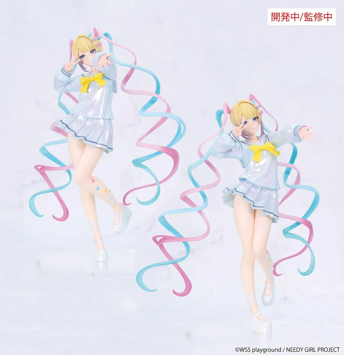 Prototype NEEDY GIRL OVERDOSE Vivit INTERNET ANGEL figure in a pale blue outfit with a yellow bow, spiraling pink-and-turquoise hair, and a peace-sign pose.