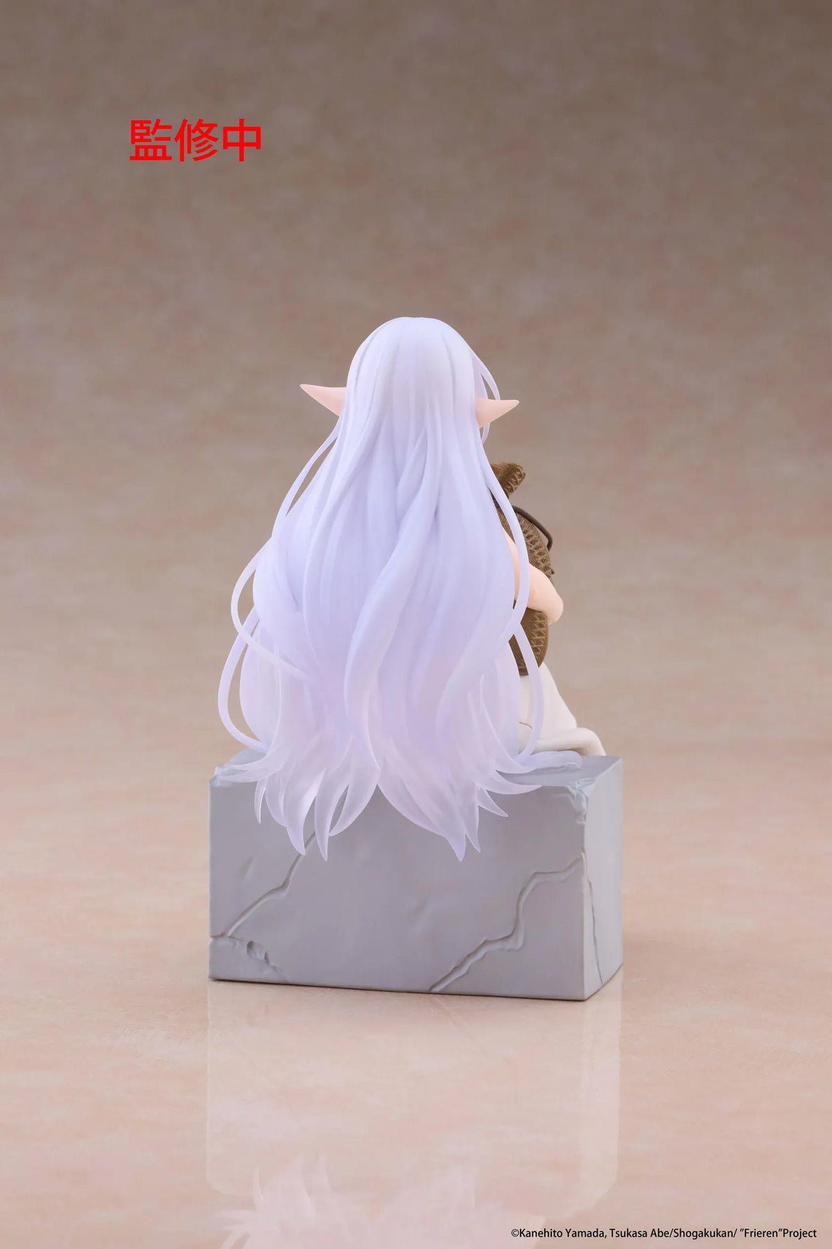Desktop Cute Frieren In Training Ver. figure seated on a gray stone block, wearing a cream dress and brown sandals while holding a sack beside rolled scrolls.