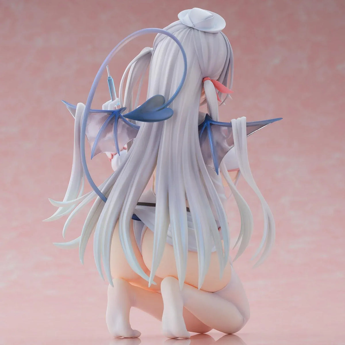 Succubus Nurse Makina figure kneeling in a white and pink nurse outfit with silver hair, batlike wings, a demon tail, and a translucent syringe.