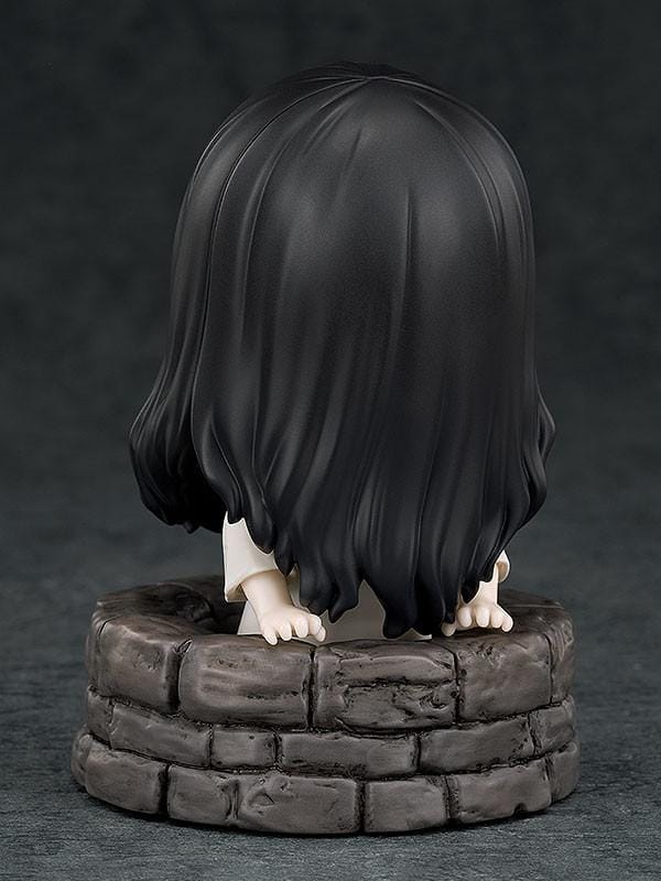 Nendoroid Sadako figure with long black hair covering her face, wearing a white dress and standing barefoot on a clear display base.