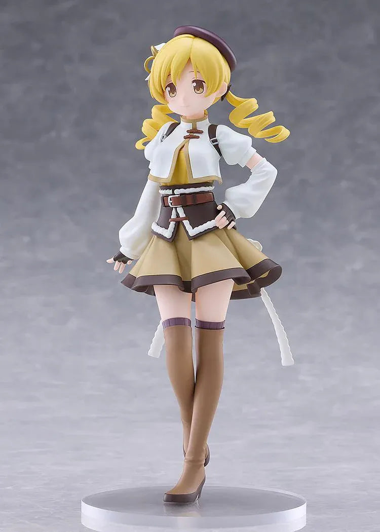 Mami Tomoe figure with blonde spiral curls, a brown hat, white and gold outfit, and tall brown boots, posing with one hand on her hip.