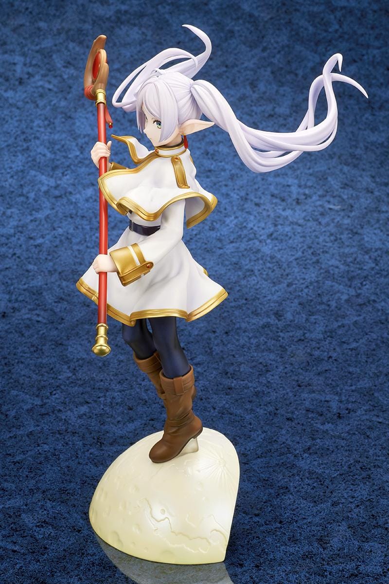 Frieren vs Aura 1/7 scale figure holding a red staff while wearing her white-and-gold mage outfit on a rounded display base.