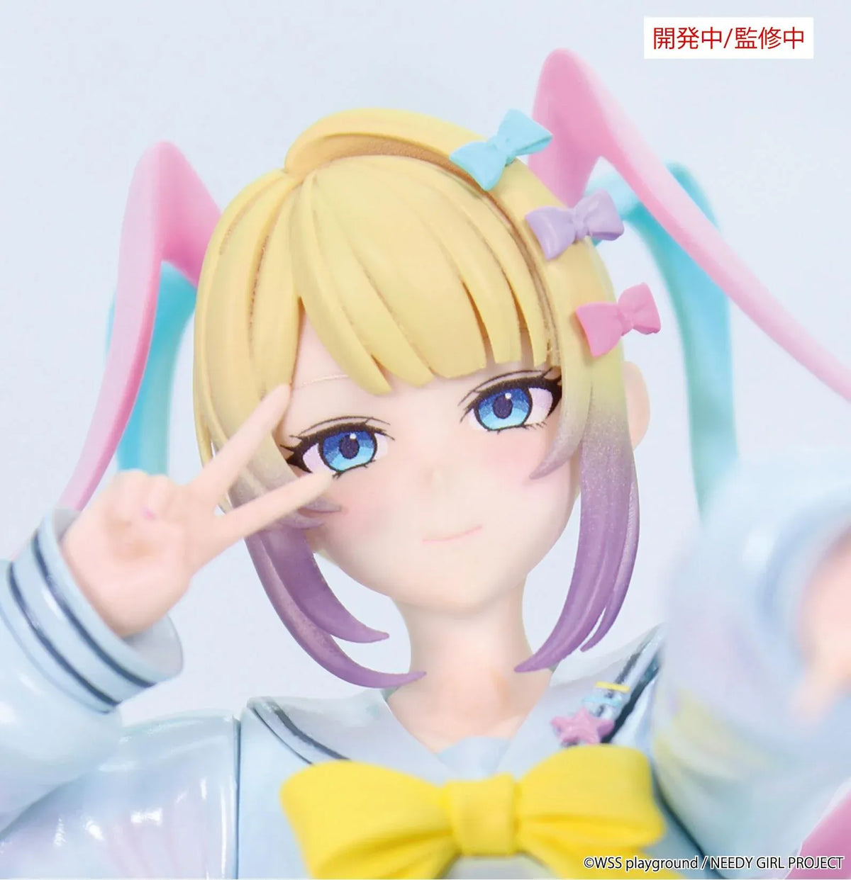 Prototype NEEDY GIRL OVERDOSE Vivit INTERNET ANGEL figure in a pale blue outfit with a yellow bow, spiraling pink-and-turquoise hair, and a peace-sign pose.