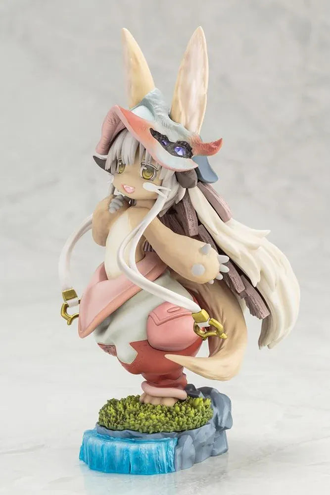 Made in Abyss The Awakening Mystery Nanachi Figure (Rerelease) featuring a fluffy rabbit-like character with long cream-colored ears, golden eyes, an oversized explorer hat, pink and beige clothing, and long flowing hair standing on a detailed scenic base with green moss, rocks, and blue water.