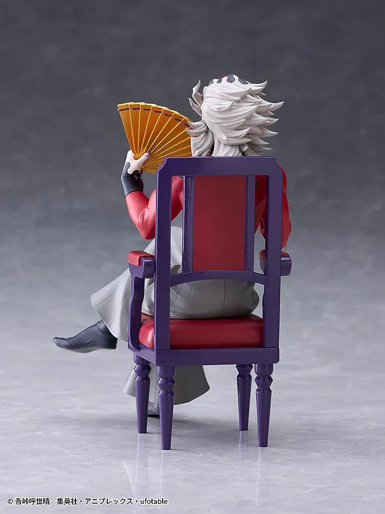 Doma figure seated cross-legged on a purple chair with red cushions, holding a gold floral fan and wearing a red top with gray trousers.