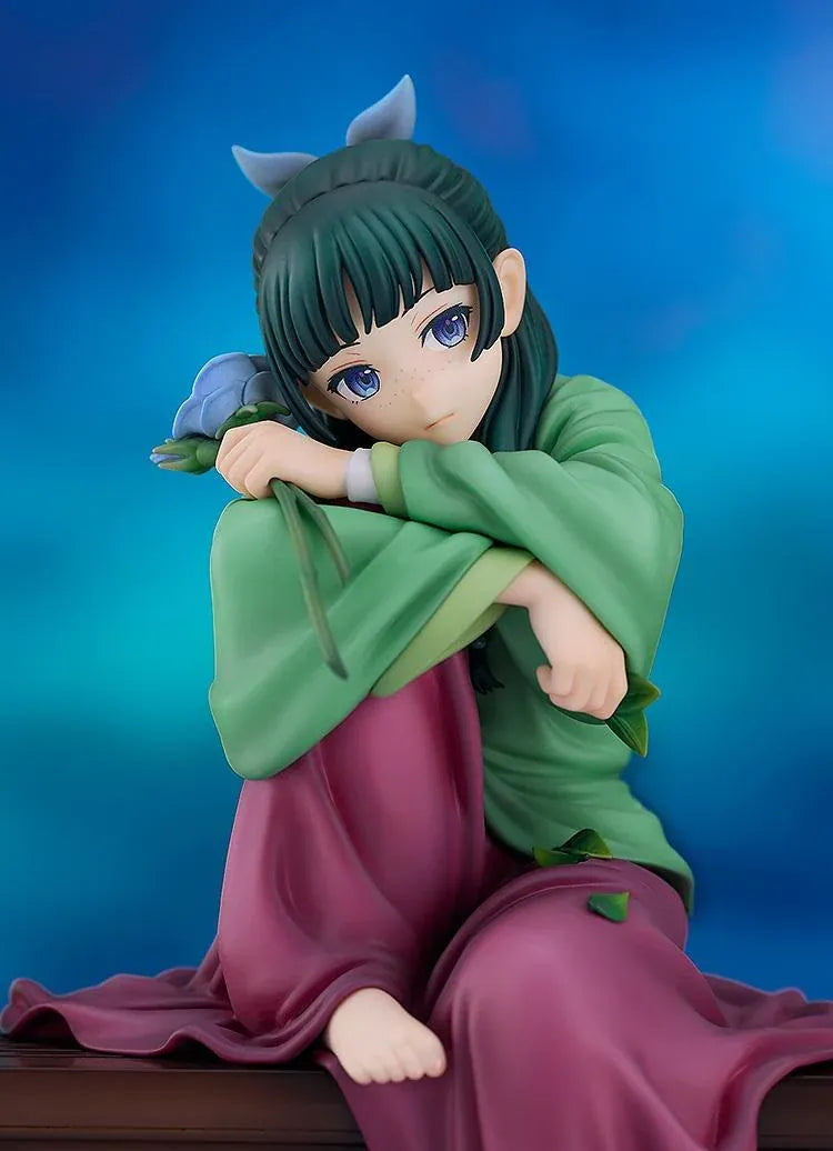 Maomao 1/7 scale figure seated barefoot on a wooden bench, wearing a green top and plum skirt, holding a blue flower beside a mortar and pestle.