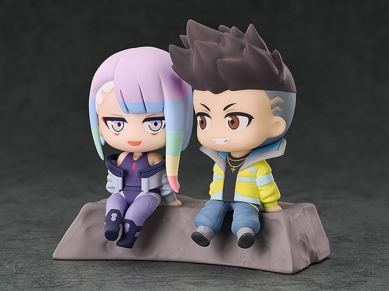 Cyberpunk: Edgerunners Qset+ David & Lucy To The Moon Figure (Rerelease) featuring chibi-style David Martinez with spiky black hair and a yellow jacket sitting beside Lucy Kushinada with pastel-colored hair and a purple futuristic outfit on a shared display base.