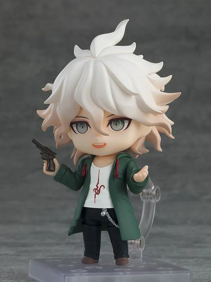 Nendoroid Nagito Komaeda with tousled white hair, pale green eyes, a green coat, white printed shirt, and black trousers, extending one hand.