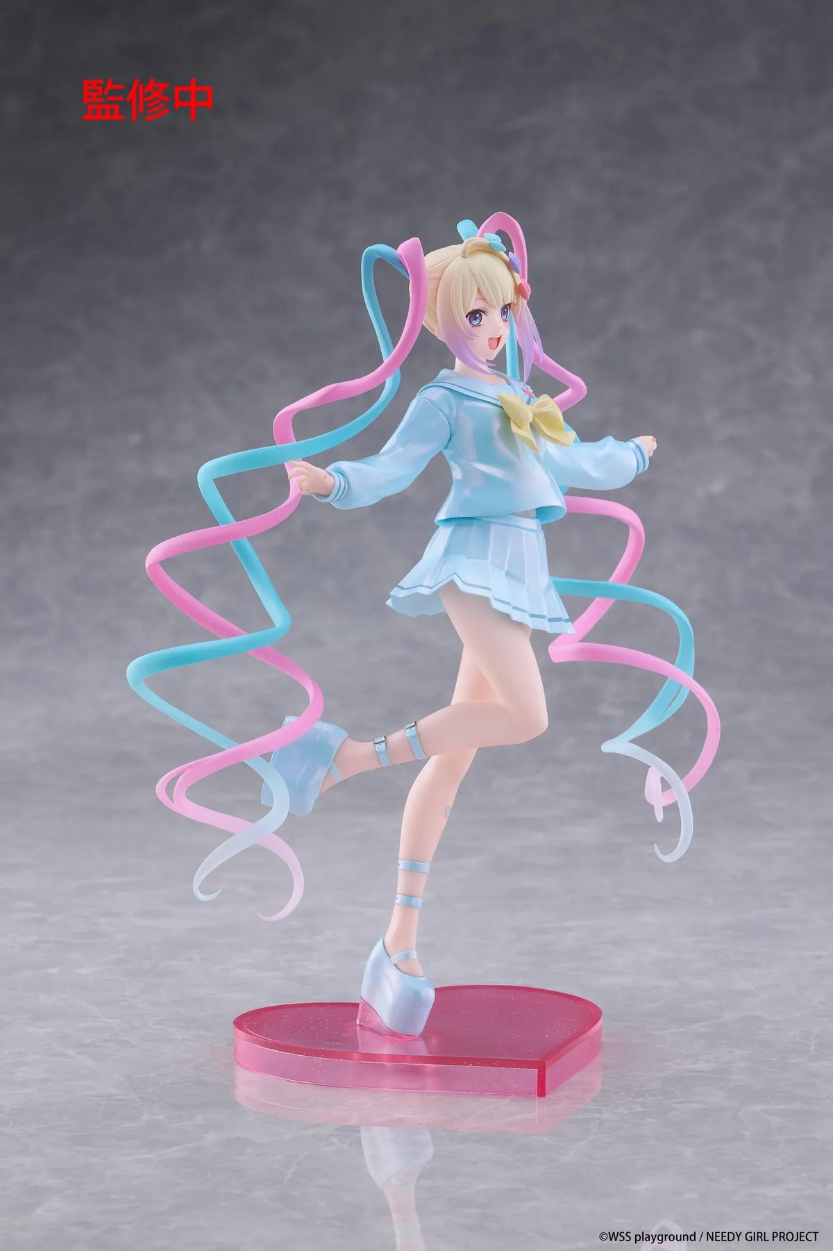Needy Girl Overdose OMGKawaiiAngel Coreful Figure featuring a blonde-haired anime girl with blue eyes, long pink and blue twin-tails, a pastel-blue sailor-style outfit, yellow bow, and matching shoes posed on a pink heart-shaped base.