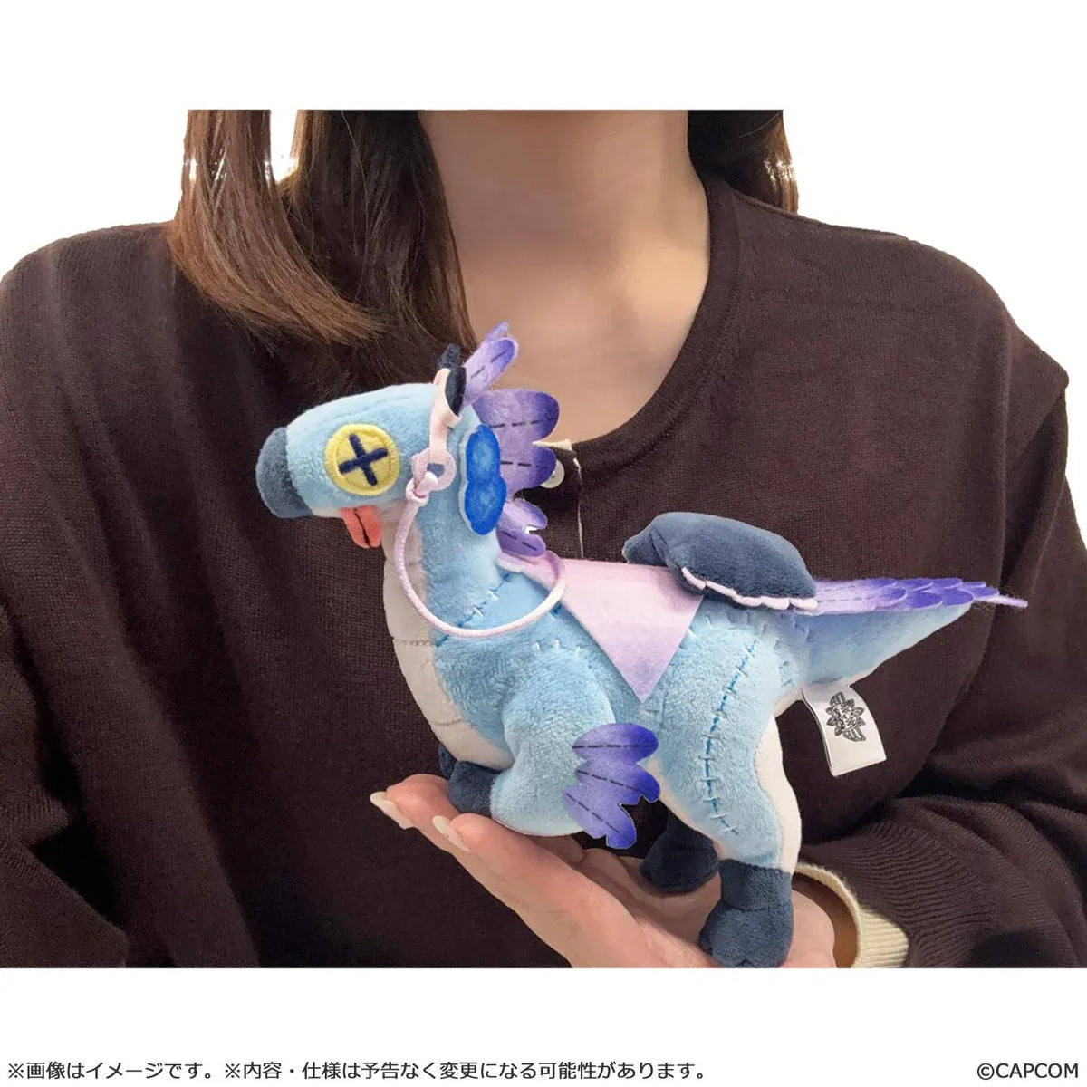 Monster Hunter Wilds Seikret Living Doll Caparison Plushie featuring a blue bird-like companion with purple feathers, button-style eyes, patchwork stitching, a decorative saddle, and dark blue feet.