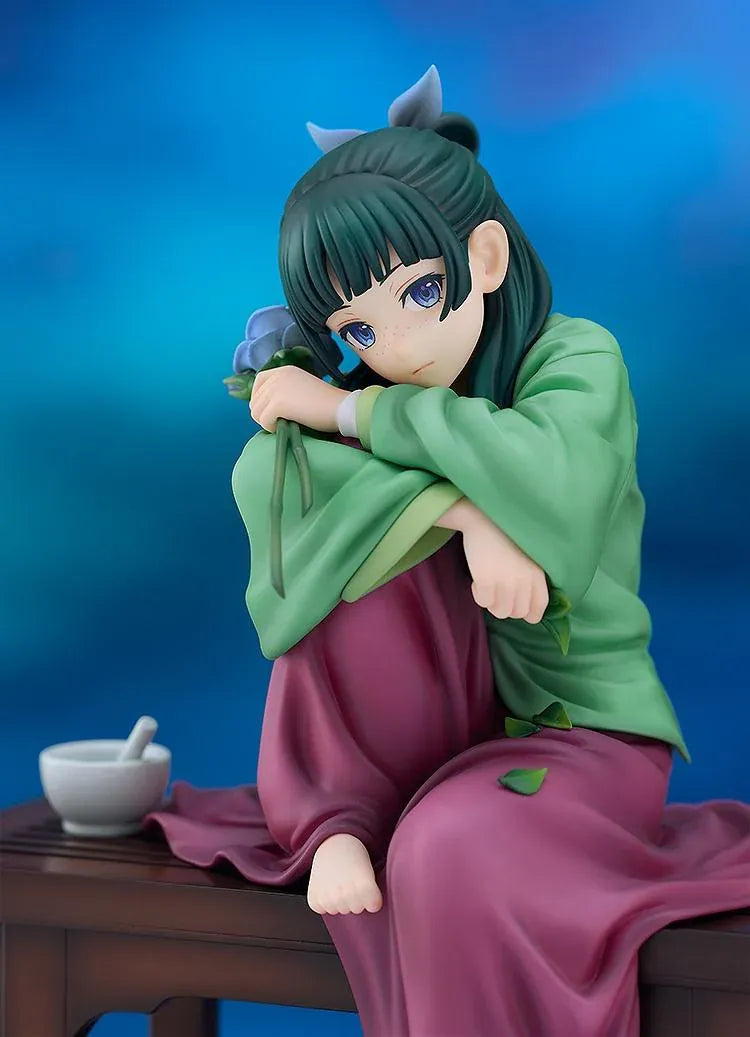Maomao 1/7 scale figure seated barefoot on a wooden bench, wearing a green top and plum skirt, holding a blue flower beside a mortar and pestle.
