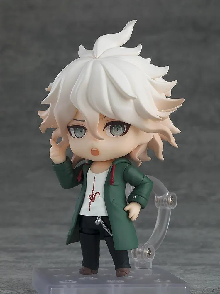 Nendoroid Nagito Komaeda with tousled white hair, pale green eyes, a green coat, white printed shirt, and black trousers, extending one hand.