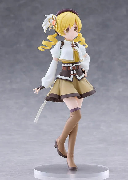 Mami Tomoe figure with blonde spiral curls, a brown hat, white and gold outfit, and tall brown boots, posing with one hand on her hip.