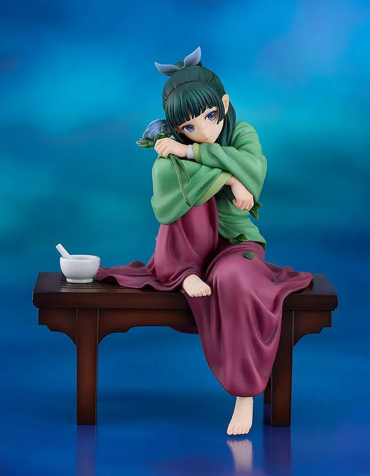 Maomao 1/7 scale figure seated barefoot on a wooden bench, wearing a green top and plum skirt, holding a blue flower beside a mortar and pestle.