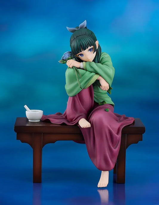 Maomao 1/7 scale figure seated barefoot on a wooden bench, wearing a green top and plum skirt, holding a blue flower beside a mortar and pestle.