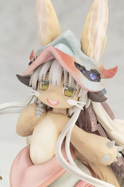 Made in Abyss The Awakening Mystery Nanachi Figure (Rerelease) featuring a fluffy rabbit-like character with long cream-colored ears, golden eyes, an oversized explorer hat, pink and beige clothing, and long flowing hair standing on a detailed scenic base with green moss, rocks, and blue water.